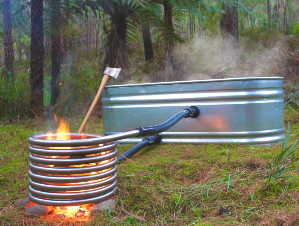 Stock tank hot tub with a wood-fired coil and steam in the forest