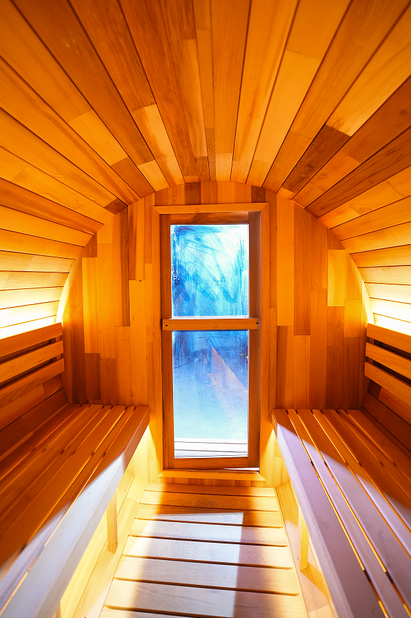 Interior de sauna de barril con bancas de madera y ventana